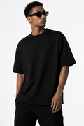 A man wearing an oversized black half sleeve t-shirt